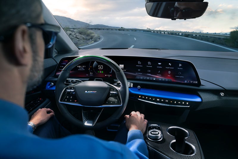 Front View of the 2026 OPTIQ-V Driving Through the Dusk Utilizing its Headlights | Cadillac of Laguna Niguel in Laguna Niguel CA