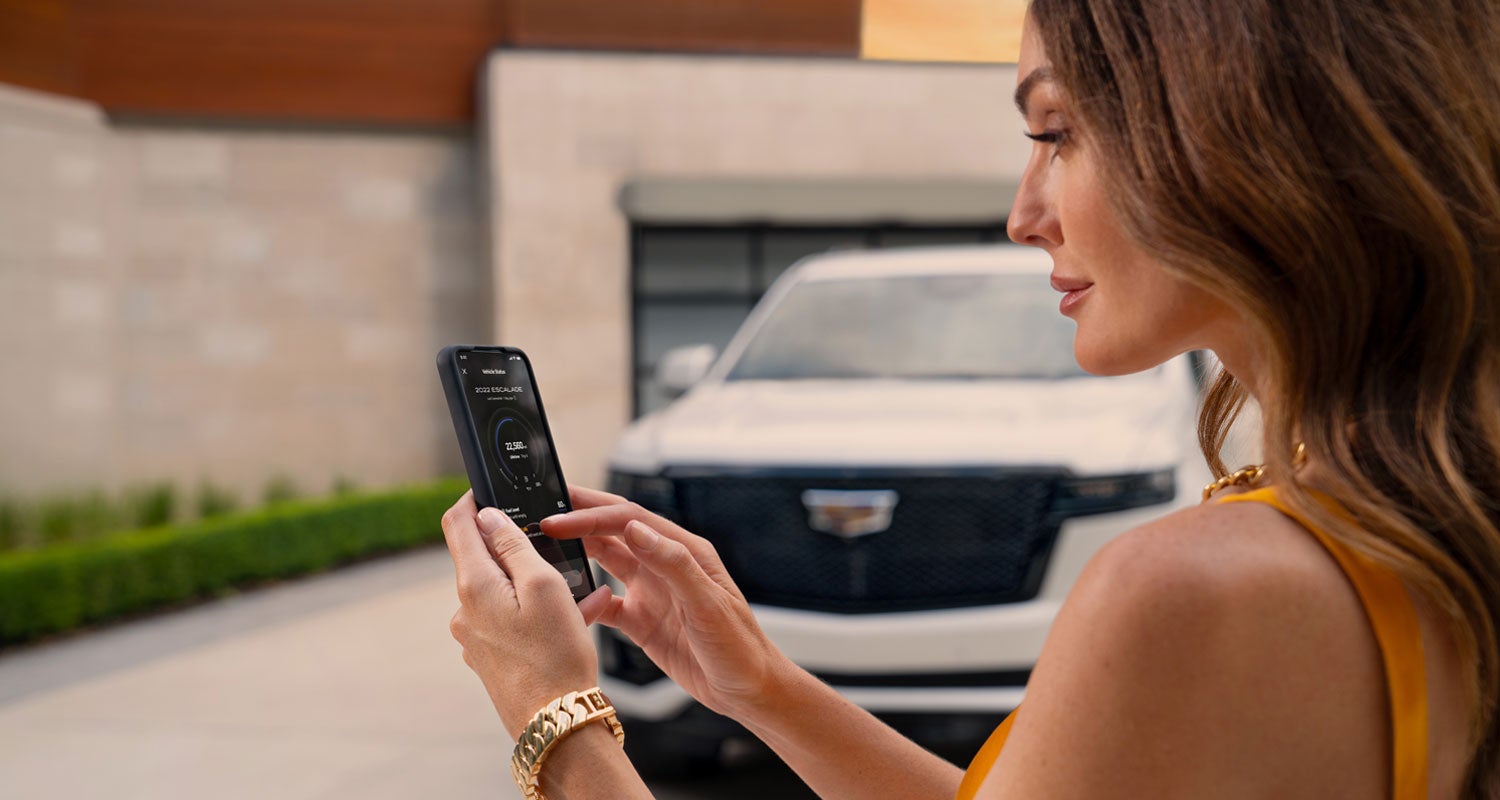 lady checking her mobile with a Cadillac vehicle background | Cadillac of Laguna Niguel in Laguna Niguel CA